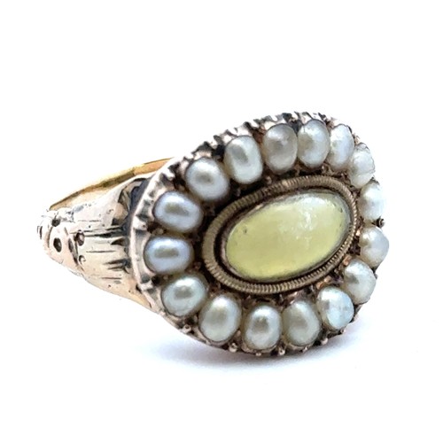 7 - A Georgian ring with a rock crytsal and yellow foil back central oval panel surrounded by a halo of ... 