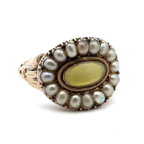 7 - A Georgian ring with a rock crytsal and yellow foil back central oval panel surrounded by a halo of ... 