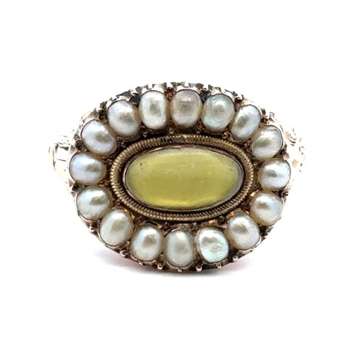 7 - A Georgian ring with a rock crytsal and yellow foil back central oval panel surrounded by a halo of ... 