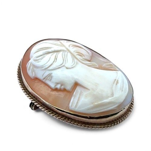 21 - A shell cameo brooch depicting a lady in profile, in yellow metal mount with rope twist edge, stampe... 
