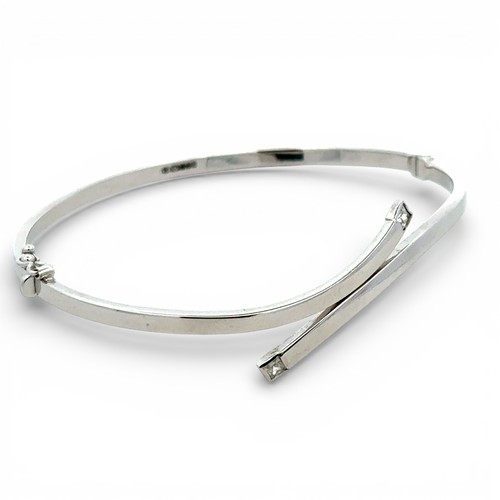 74 - 9ct white gold twist bangle, both ends set with a princess cut  white stone, width 65mm