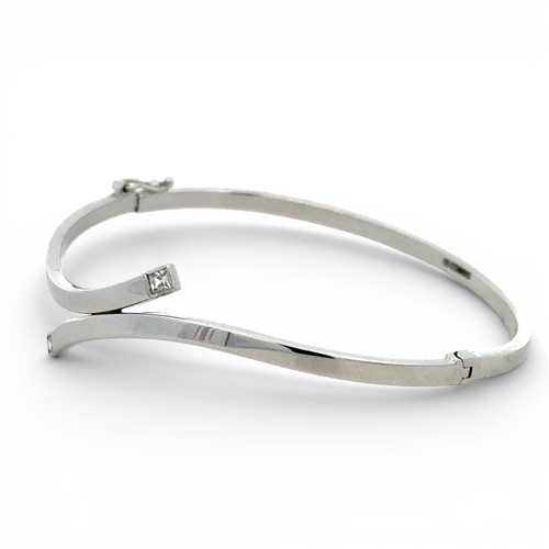 74 - 9ct white gold twist bangle, both ends set with a princess cut  white stone, width 65mm