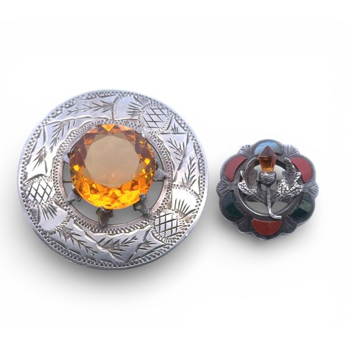 87 - Two silver brooches. A 'Scottish' circular brooch with central orange paste stone set in a raised cl... 