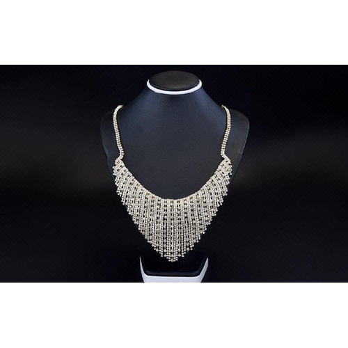 359 - White Crystal Waterfall Necklace, the centre front with a shaped, flexible piece covered with differ... 