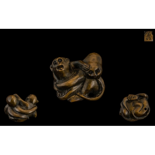 837 - An Oriental Boxwood Netsuke in the form of a monkey fighting an octopus. Signed to underside. Please... 