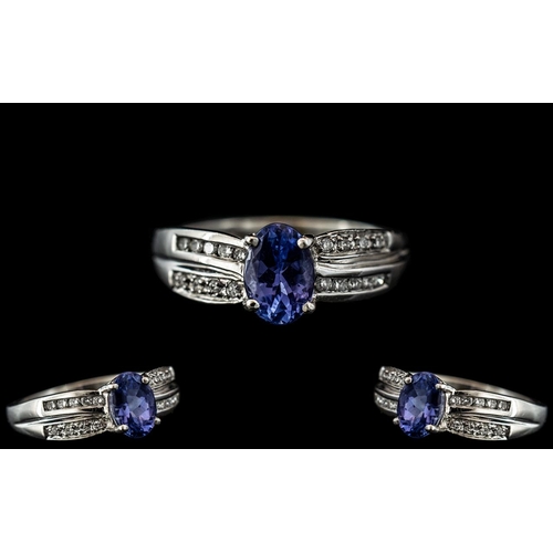 80 - A Platinum Diamond Ring set with an oval blue faceted stone between channel set round brilliant cut ... 