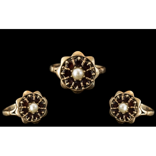 255 - 9ct Gold Dress Ring, set with a central seed pearl surrounded by garnets, stamped 9ct.