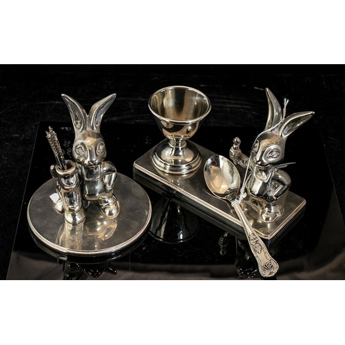 1438 - Two Table Top Stainless Steel Ornaments comprising an egg cup stand with spoon, and Peter Rabbit fig... 