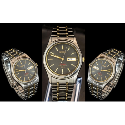 224 - Seiko - Titanium Day-Date Gold and Steel Gent's Wrist Watch, with black dial and gold markers.  No. ... 