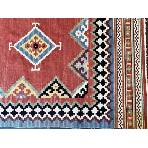 1056 - An Aztec Design Woolen Rug, Salmon Ground, Bright Geometric Decoration, 310 x 250 cm.