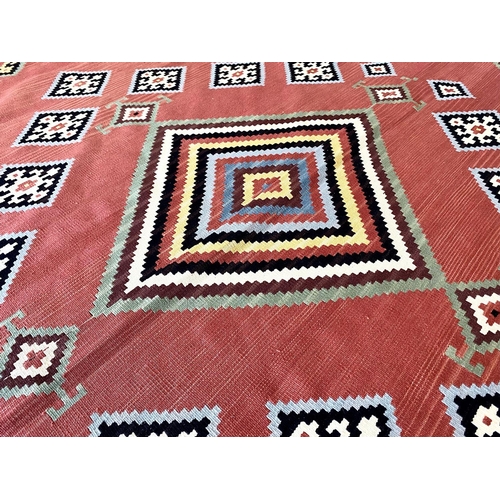 1056 - An Aztec Design Woolen Rug, Salmon Ground, Bright Geometric Decoration, 310 x 250 cm.