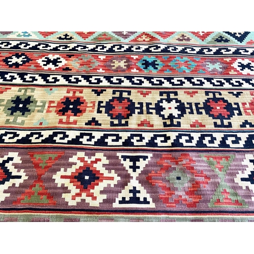 1058 - An Aztec Design Woolen Rug, Multi Coloured Ground, Geometric Black And White Border, 280 x 195 cm.