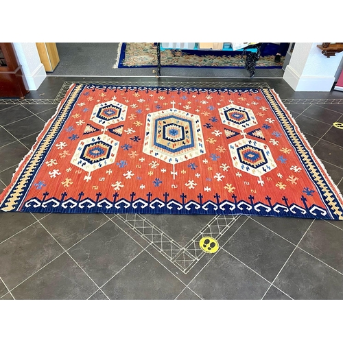 1059 - An Aztec Design Woolen Rug, Red Salmon Ground, Geometric Blue And White Border, 310 x 255 cm.