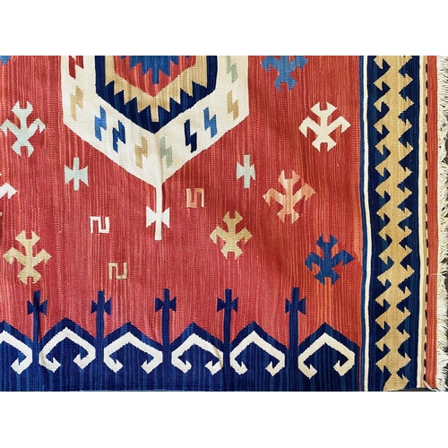 1059 - An Aztec Design Woolen Rug, Red Salmon Ground, Geometric Blue And White Border, 310 x 255 cm.