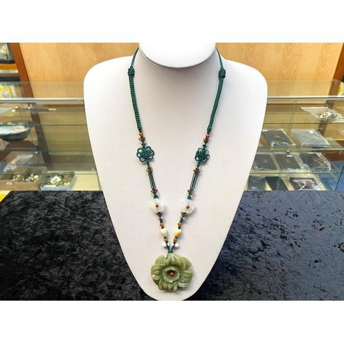 449 - Two Green Jade Pendant Necklaces, one having a large, carved, floral pendant, on a thread necklace d... 