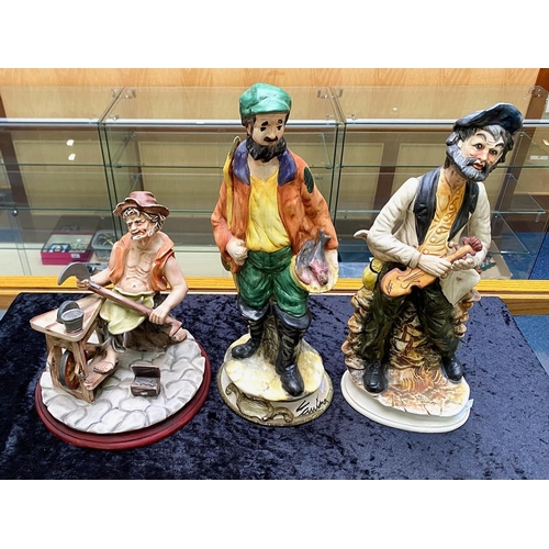 617 - Three Capo di Monte Figures, comprising a man sharpening tools, a violin player and a fish seller, s... 