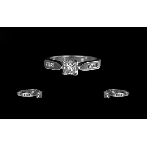 233 - A Platinum Diamond Engagement Ring, set with a central princess cut diamond, four round cut diamond ... 