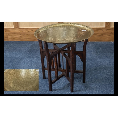 1060 - Middle Eastern Brass Topped Folding Table, brass engraved top on folding wooden legs.  Diameter 23''... 