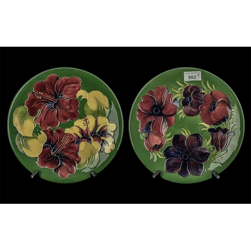 582 - Two Moorcroft Plates, 10'' diameter, one dark green with Hibiscus pattern,  one dark green with Clem... 