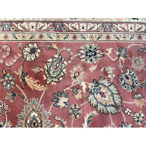 1038 - Large Royal Keyshan Wool Carpet, pink background with floral border and fringing, (some marks), meas... 