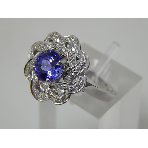 102 - Tanzanite and diamond cluster ring, central round cut tanzanite with a surround of round brilliant c... 