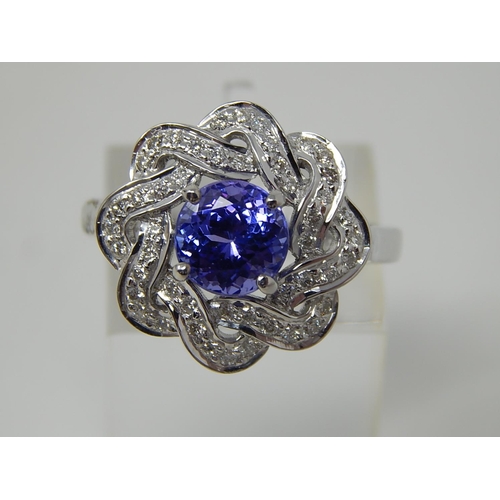 102 - Tanzanite and diamond cluster ring, central round cut tanzanite with a surround of round brilliant c... 