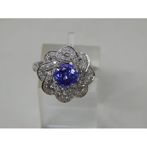 102 - Tanzanite and diamond cluster ring, central round cut tanzanite with a surround of round brilliant c... 