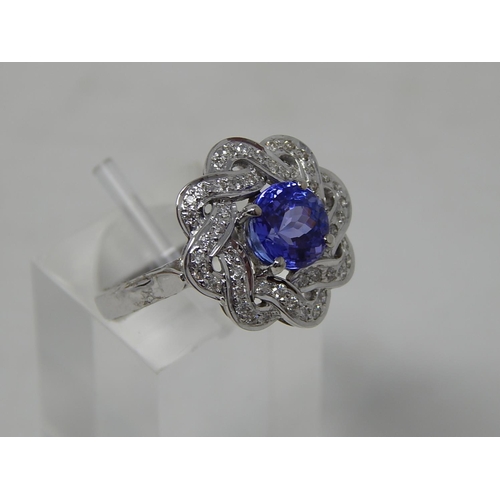 102 - Tanzanite and diamond cluster ring, central round cut tanzanite with a surround of round brilliant c... 