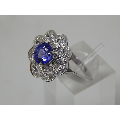 102 - Tanzanite and diamond cluster ring, central round cut tanzanite with a surround of round brilliant c... 