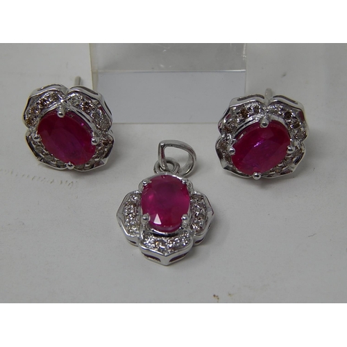 110 - Ruby and diamond pendant, ring and earring set, each item set with an oval cut ruby and a surround o... 