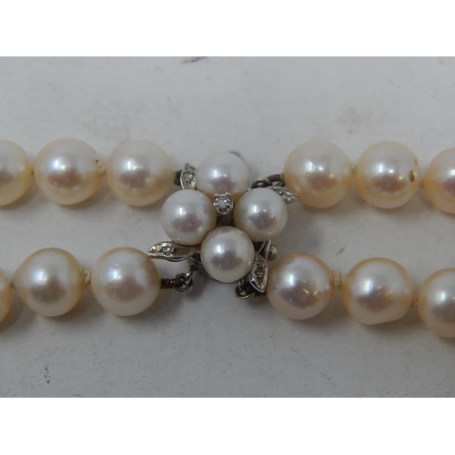 151 - Two row pearl necklace, pearls approximately 7.5mm, with a floral design clasp set with four smaller... 