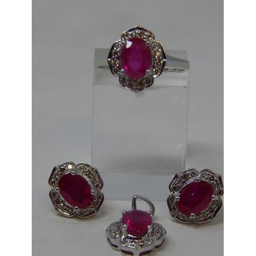 64 - Ruby and diamond pendant, ring and earring set, each item set with an oval cut ruby and a surround o... 