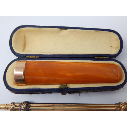 24 - A vintage Gold Propelling pencil in 14ct Gold gross weight 13g; An amber cigarette holder with Gold ... 