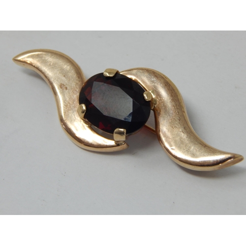 252 - 9ct Gold (tested) Brooch set with a central garnet: Width 5.4cm: gross weight 8.78g