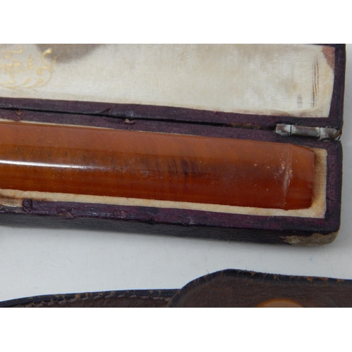 107 - Two Gold Mounted Amber Cigarette Holders together with a further cigarette holder in original fitted... 