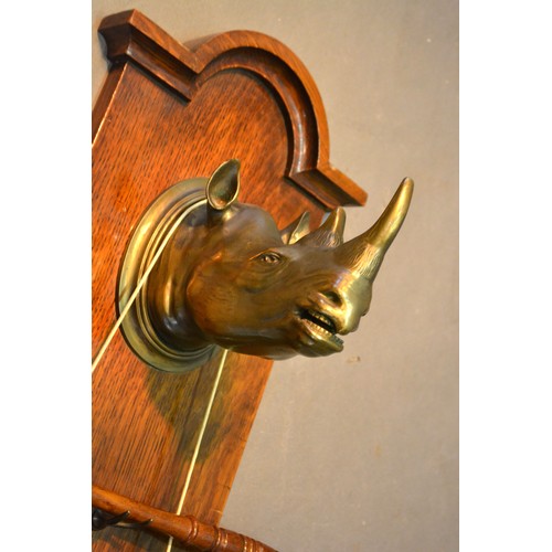 355 - An Edwardian Dinner Gong in the form of a Rhinoceros Head attached to an oak board, 68 cms long