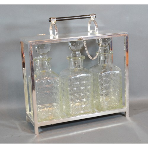 244 - A Silver Plated Tantalus, the hinged top above three cut glass decanter with stoppers 28cm by 10cm a... 