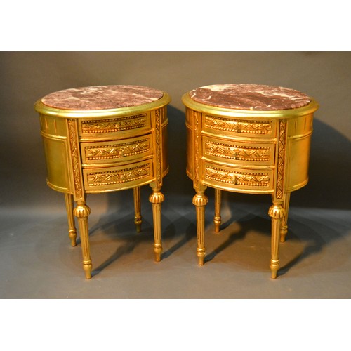 536 - A Pair of Oval Gilded Three Drawer Chests each with a rouge marble top above three drawers raised up... 