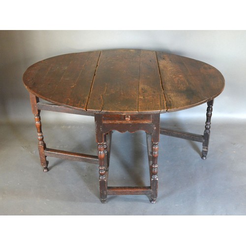 547 - A George III Oak Oval Gate Leg Dining Table with a frieze drawer raised upon turned legs with stretc... 