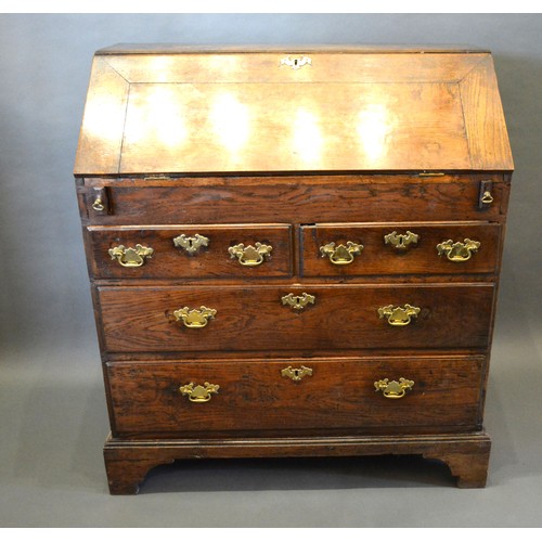 394 - A George III Oak Bureau, the fall front enclosing a fitted interior with well above two short and tw... 