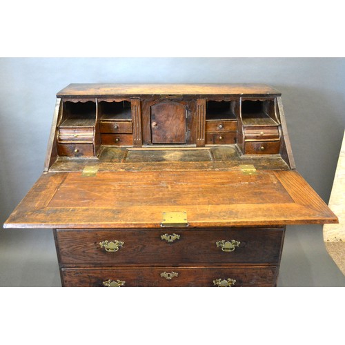 394 - A George III Oak Bureau, the fall front enclosing a fitted interior with well above two short and tw... 