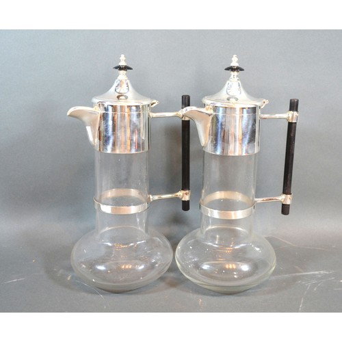 92 - A pair silver plated and glass claret jugs in the style of Christopher Dresser with ebonies handles,... 