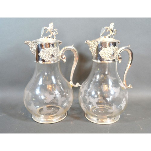 94 - A pair of silver plated and engraved glass claret jugs, each engraved with grape vine, the covers wi... 