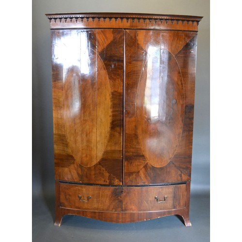 439 - An Edwardian mahogany bow fronted wardrobe, the moulded cornice above two oval inlaid doors above a ... 