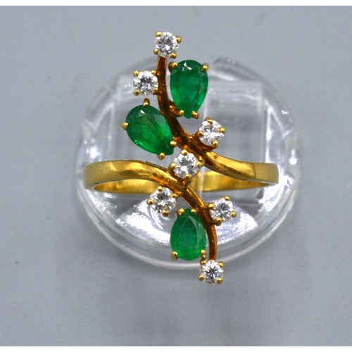 137 - An 18ct Gold Emerald And Diamond Ring set with three emeralds and seven diamonds of crossover form, ... 