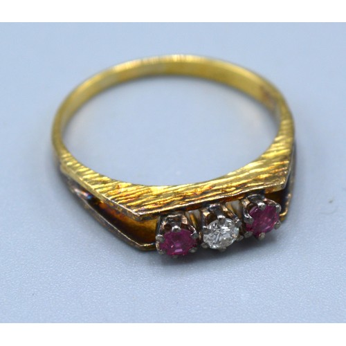 105 - An 18ct Yellow Gold Ruby And Diamond Ring set with central diamond flanked by two rubies within a pi... 