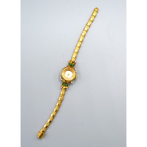 121 - A Gubelin Ladies' 18ct. Gold Cased Wrist Watch set with diamonds and emeralds and with 18ct. gold st... 