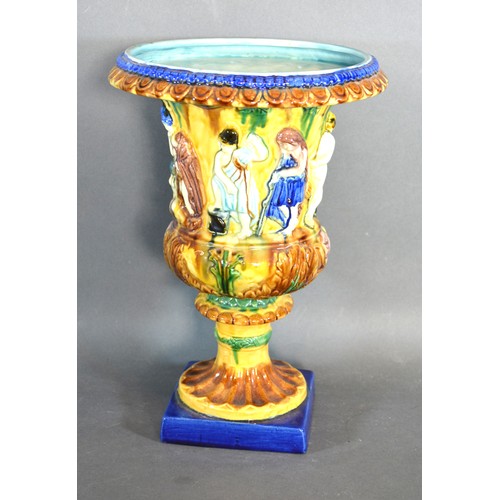 27 - A Majolica Urn decorated with a band of figures upon a shaped stepped base 32 cms tall