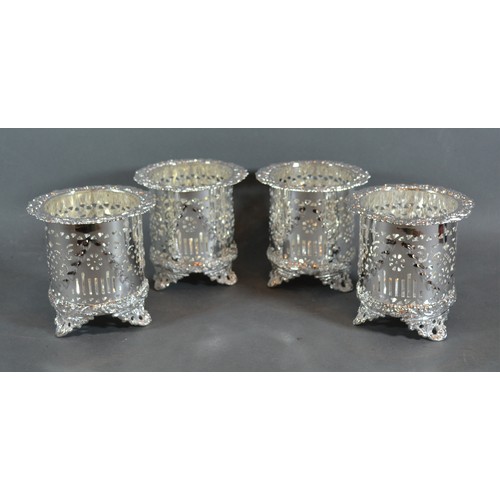 151 - A set of four silver plated bottle stands of pierced from each with three low scroll feet, 12cms tal... 