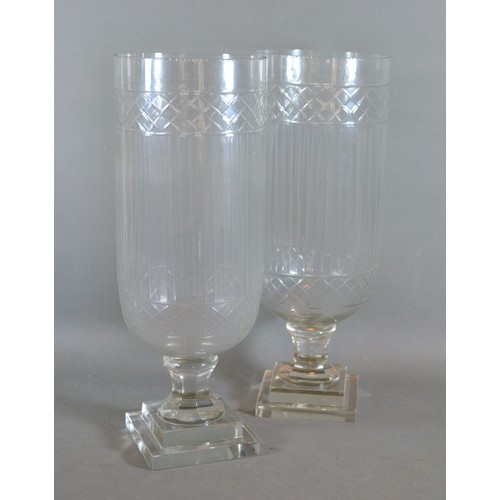 12 - A pair of star cut glass storm vases with square pedestal bases, 40cms tall
